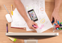 Tips for Fostering Effective Sales Leadership Within Your Company A person working at a wooden desk with papers out and in front of a large computer.