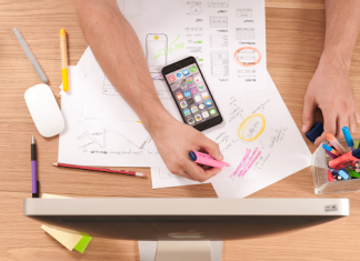 Tips for Fostering Effective Sales Leadership Within Your Company A person working at a wooden desk with papers out and in front of a large computer.